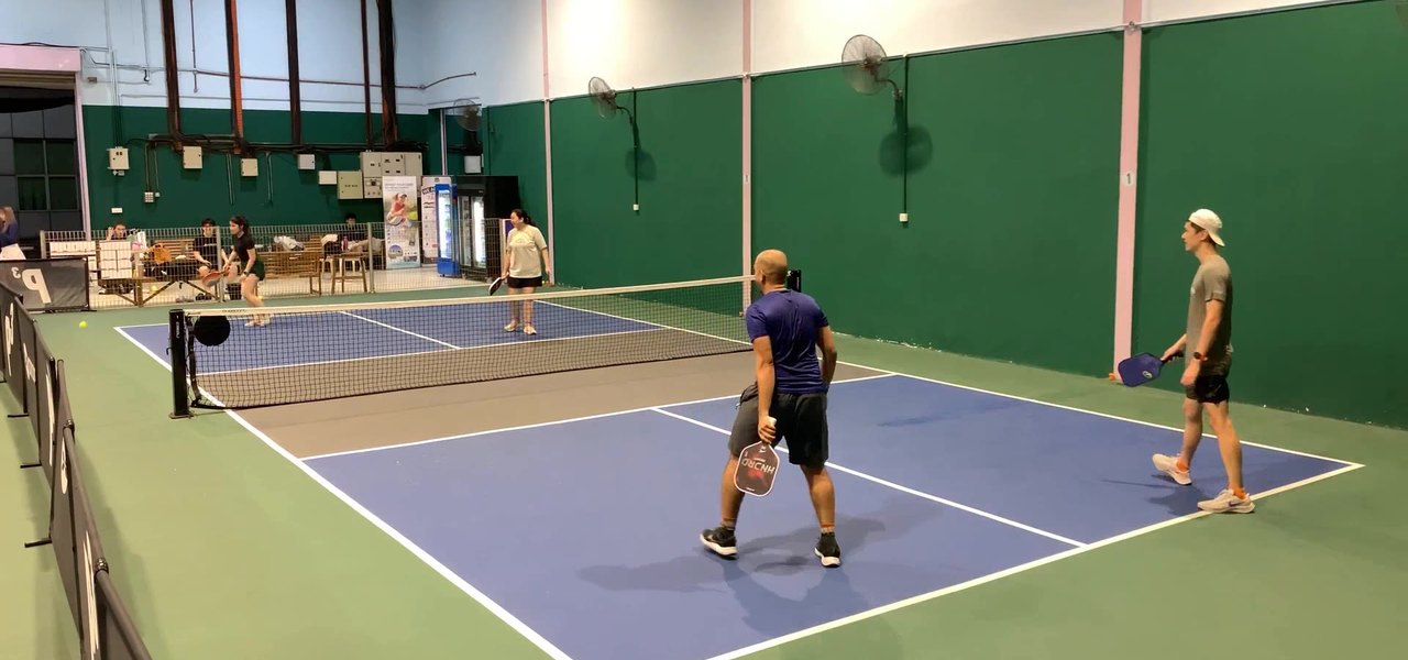 A doubles match framed in a phone held sideways, recording